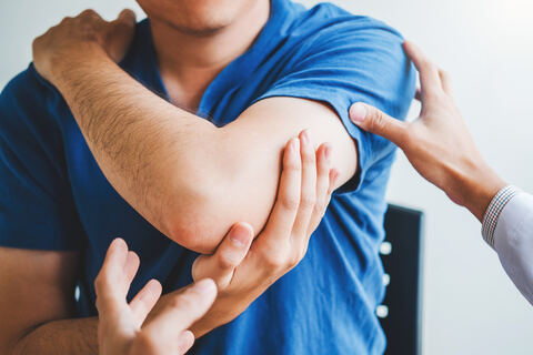 Anwendung der manuellen Schmerztherapie am Arm eines Patienten durch gezielte Handgriffe der Therapeutin.